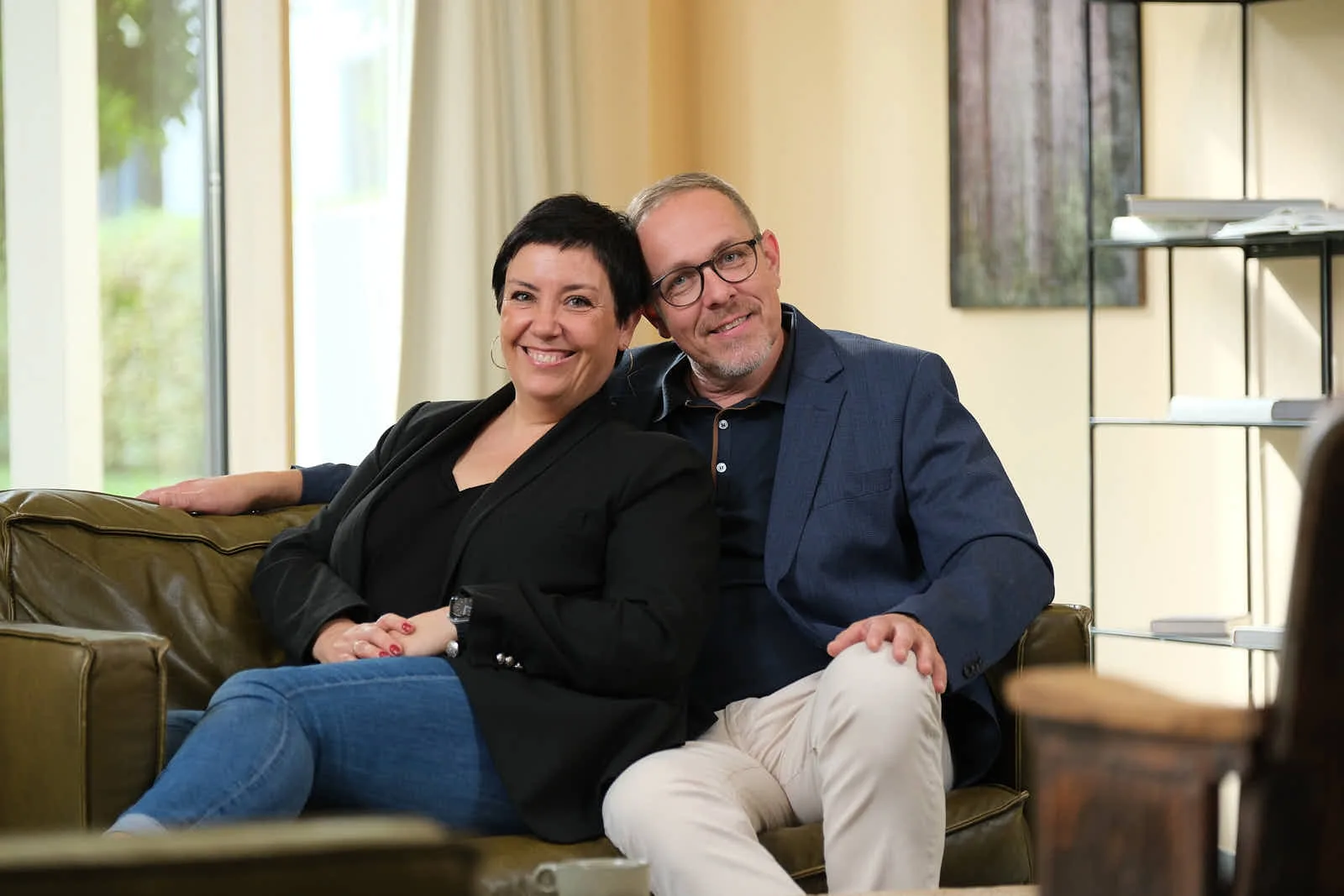 Wiebke und Ingo Anton sitzen eng beieinander auf dem Sofa und lächeln